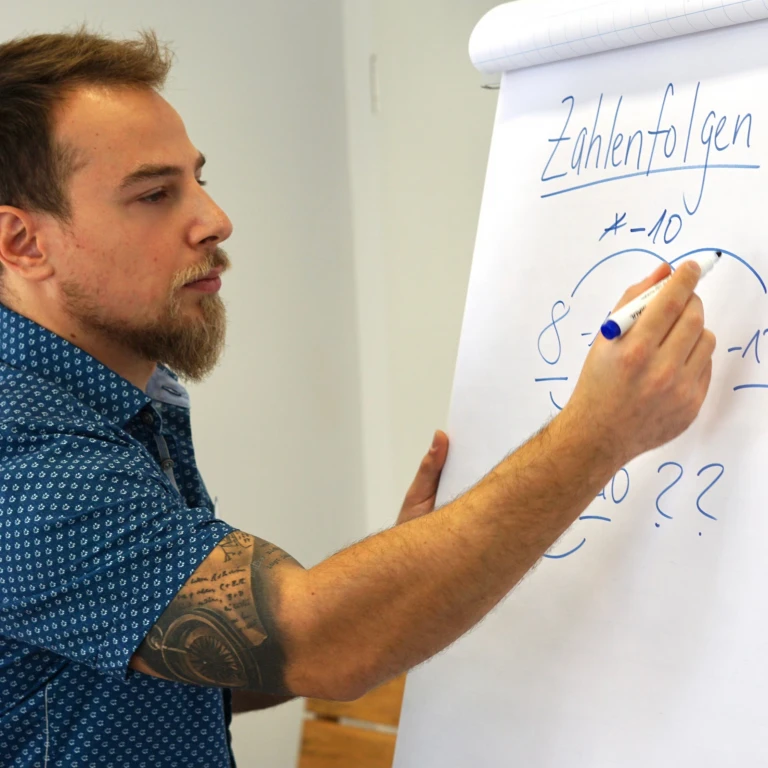 Deniz Tafrali erklärt Zahlenfolgen am Flipchart in einem get-to-med-Kurs