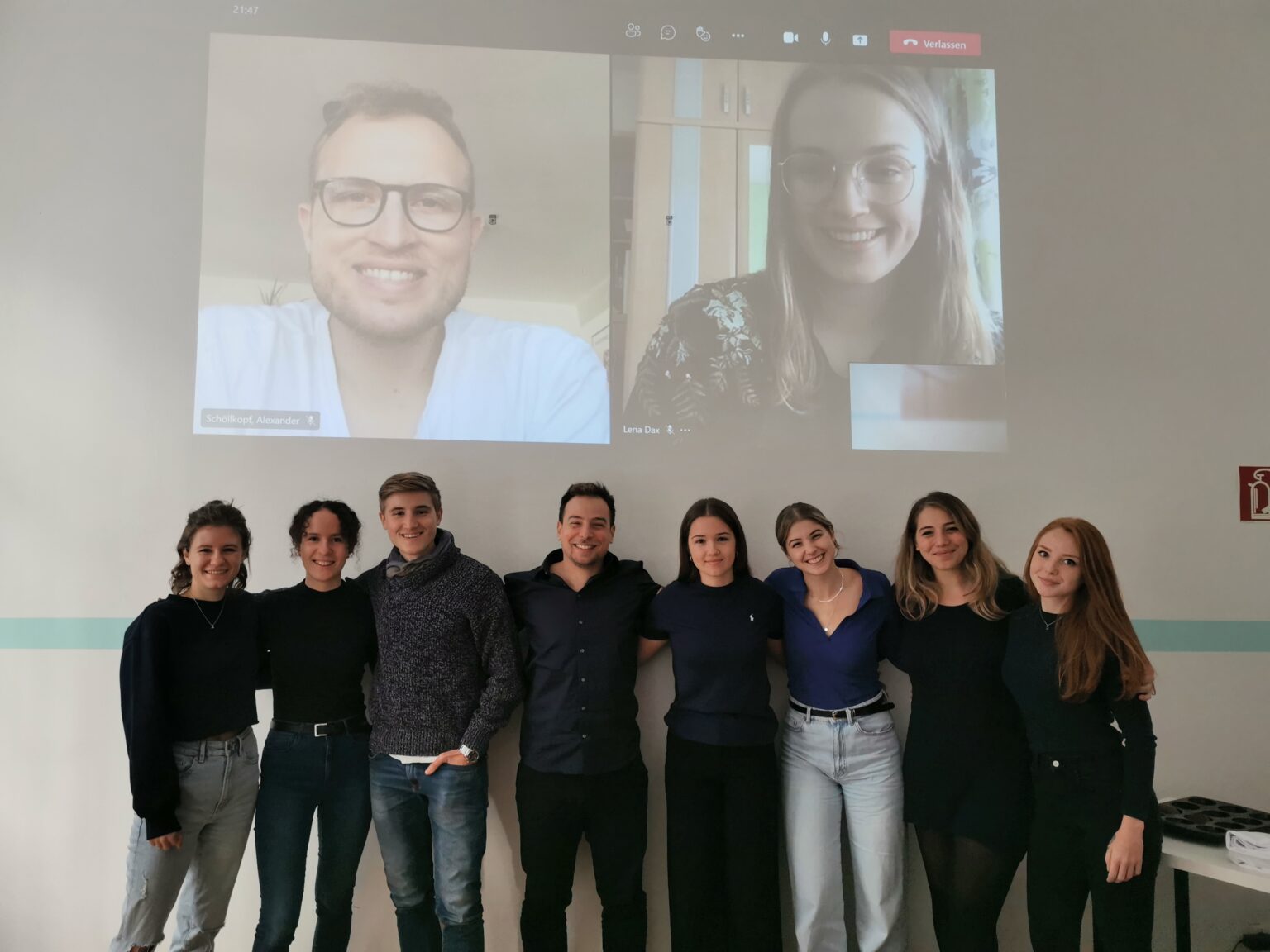 Das Team von get-to-med vor einer Leinwand, zwei Teammitglieder per Video zugeschaltet
